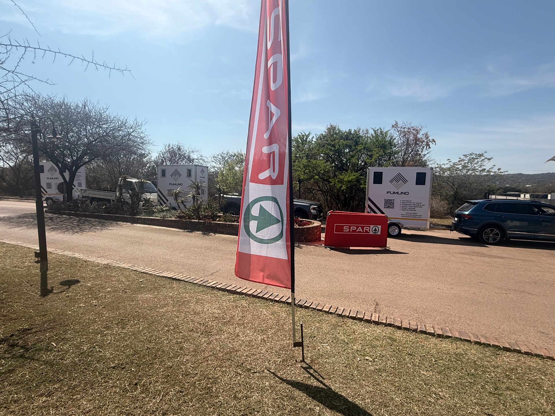 Two Fumuno VIP mobile toilet trailers and a Fumuno delivery bakkie set up in the parking area of a SPAR sponsored outdoor event in Gauteng.