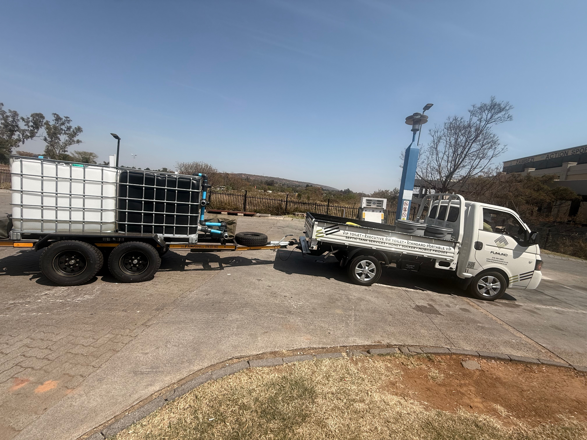 Fumuno branded bakkie hitched to a double-axle water tanker trailer carrying two IBC water tanks with pump and hose fittings — water delivery for sites and events in Gauteng.